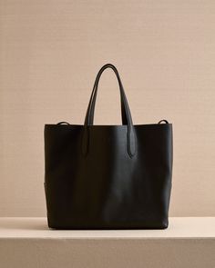 The Eleanor Tote is the perfect slouchy, easy tote bag. Crafted from the softest Tumbled Grain Calfskin leather in Black with tonal stitching, the Eleanor Tote features a third strap which fastens using our signature collar studs. Black Bag With Grained Texture For Everyday Use, Black Bags With Grained Texture For Everyday Use, Everyday Top Handle Shoulder Bag With Grained Texture, Classic Grained Texture Shoulder Bag For Work, Everyday Black Bag With Grained Texture, Classic Grained Texture Shoulder Bag For Everyday Use, Everyday Leather Shoulder Bag With Grained Texture, Classic Bags With Grained Texture For Work, Classic Shoulder Bag With Grained Texture For Daily Use