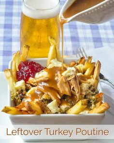 a person pouring gravy on some french fries