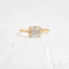 Emerald Cut Cluster Moissanite Bridal Ring, Colorless Moissanite Engagement Ring, 14K Solid Gold Proposal Ring, Unique Jewelery ➜ 𝗠𝗮𝗶𝗻 𝗦𝘁𝗼𝗻𝗲 𝗗𝗲𝘁𝗮𝗶𝗹𝘀 ✦ Shape : Emerald Cut ✦ Type : Moissanite ✦ TCW : 1 CT (Shown) ✦ Size : 7 x 5MM ✦ Process : Handmade ➜ 𝗦𝗶𝗱𝗲 𝗦𝘁𝗼𝗻𝗲 𝗗𝗲𝘁𝗮𝗶𝗹𝘀 ✦ Shape : Round Cut ✦ Type : Moissanite ✦ Piece : 12 ✦ TCW : 0.18 CT ✦ Size : 1-2 MM ➜ 𝗥𝗶𝗻𝗴 𝗗𝗲𝘁𝗮𝗶𝗹𝘀 ✦ Band Width : 1.3 MM (App.) ✦ Metal Purity : Solid Gold [10KT, 14KT, 18KT] ✦ Color : Alt Wedding, Melanie Casey, Ring Emerald Cut, Minimal Ring, Basket Setting, Ring Emerald, Wedding Vibes, Diamond Settings, Proposal Ring