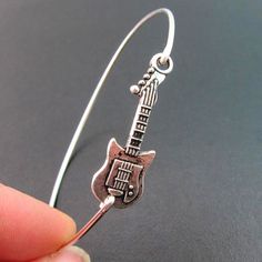 "Guitar Bracelet - Country Music Jewelry - Rock Music Jewelry A silver tone guitar charm has been transformed into a silver guitar bangle bracelet with a silver filled band. This silver guitar Jewelry is the perfect gift for music lover, gift for music teacher, or musician gift. I can also make this guitar bangle bracelet with a sterling silver band for an additional $10. If you would like this option for your country jewelry or rocker jewelry select from options when ordering. This silver guita Rocker Chic Jewelry, Lover Guitar, Guitar Bracelet, Guitar Lover Gifts, Rocker Jewelry, Guitar Jewelry, Music Bracelet, Silver Guitar, Guitar Lover