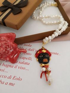 Sicilian necklace made of: - Freshwater Pearls, irregular shape (8 mm - 10 mm), white color; - Sicily Ceramic Head; - Brass chain; - Red Coral branches; - Closure: Gold plated 925 Sterling Silver ring. Total lenght : 49,50 cm / 19,48 inches * SHIPPING * Your order will be shipped within 1-3 business days from your purchase. You can choose between 2 shipping methods: STANDARD MAIL (NOT TRACEABLE) It is a cheap and fast shipping method, but NOT TRACEABLE. Chapeau Atelier is not responsible for any Artisan Necklace With Pearl Charm As Gift, Artisan Pearl Necklace Gift, Handmade Baroque Pearl Beaded Necklace As Gift, Handmade Beaded Baroque Pearl Necklace As A Gift, Beaded Pearl Pendant Necklace As A Gift, Round Beaded Necklace With Pearl Pendant As Gift, Gift Pearl Drop Pendant Beaded Necklace, Gift Beaded Pendant Necklace With Pearl Drop, Gift Pendant Beaded Necklace With Pearl Drop