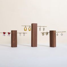 three pairs of earrings are hanging from wooden posts with earring hooks attached to them