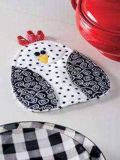 a black and white plate with a chicken on it next to a red pot holder