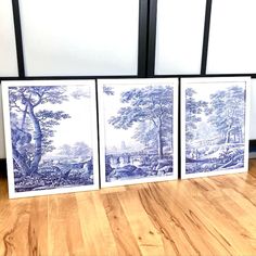 three blue and white paintings sitting on top of a wooden floor next to each other