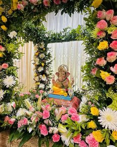 there is a mirror with flowers around it and a statue in the middle surrounded by greenery