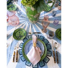 the table is set with plates, silverware, and flowers in vases on it