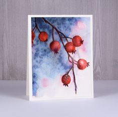 a card with some red berries hanging from it's branch on a white background