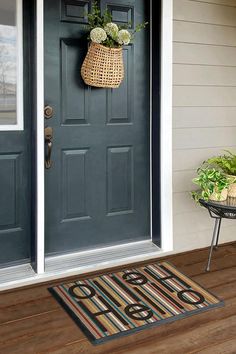 the front door is painted blue and has a basket with flowers on it, along with a potted plant