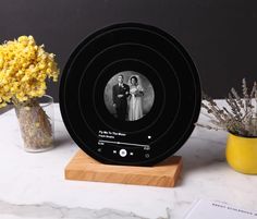 a black and white photo on a wooden stand next to yellow vases with dried flowers