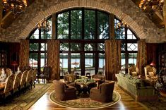 a living room filled with lots of furniture and large windows overlooking the lake in front of it