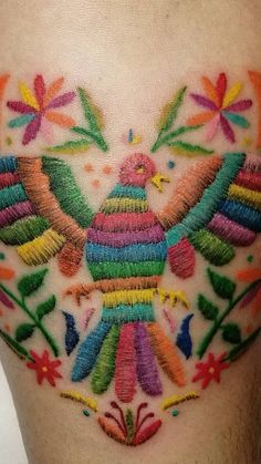 a colorful bird tattoo on the thigh