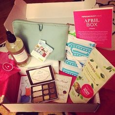 an open box filled with various items on top of a wooden table next to a pink bag