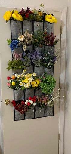 a wall hanging planter filled with lots of different types of flowers on it's side