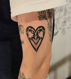 a woman's arm with a heart shaped tattoo on it