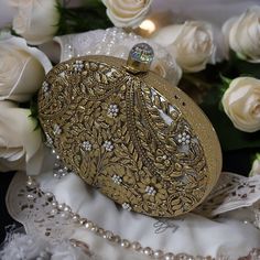 a gold purse sitting on top of white roses