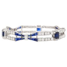 Indulge in the timeless allure of Art Deco with our stunning Blue Sapphire and Diamond Bracelet set in platinum. This exquisite piece embodies the essence of Art Deco design, boasting a perfect blend of quintessential Art Deco symmetry and vibrant contrast. The captivating blue sapphires and dazzling diamonds are meticulously arranged in a symmetrical geometric pattern, echoing the era's iconic style. The focal point showcases three stunning Emerald-cut Blue Sapphires, totaling 4 carats. Complem Timeless Blue Bracelet For Formal Occasions, Luxury Blue Sapphire Bracelets, Luxury Sapphire Bracelet, Formal Blue Bracelet With Polished Finish, Elegant Hand Set Blue Bracelet, Elegant Blue Hand-set Bracelet, Elegant Blue Hand Set Bracelets, Luxury Blue Tennis Bracelet, Luxury Blue Bracelets With Hand Set Details