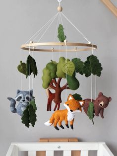 a baby crib with stuffed animals hanging from it's sides and trees on the ceiling