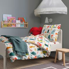 a child's bedroom with grey walls, white bedding and wooden flooring