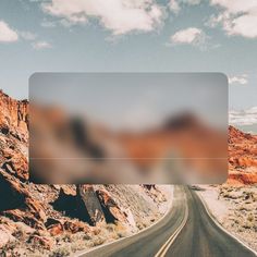 an empty road in the middle of desert with mountains and clouds behind it on a sunny day