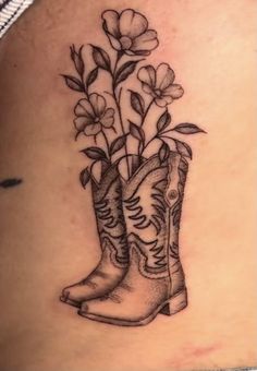 a tattoo design with boots and flowers on the back of a woman's stomach