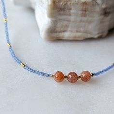 The pacific blue color of this necklace is one of my favorite trending colors. And when they are paired with Sunstone, the two colors pop in contrast. This coral and blue combination is perfect to give you all of the warm beachy vibes you could want! Sunstone is associated with the Sun's radiant energy. This is a stone that enhances your personal power and instills your life with joy, courage and optimism. This is a stone that you want close to you at all times. Colors: This beaded necklace feat Adjustable Light Blue Necklaces With Natural Stones, Everyday Blue Bohemian Beaded Necklace, Everyday Bohemian Blue Beaded Necklace, Blue Beaded Everyday Necklace, Blue Gemstone Necklace For Beach, Blue Gemstone Jewelry For The Beach, Minimalist Blue Jewelry For Beach, Adjustable Blue Ocean-inspired Necklace, Blue Beaded Necklace With Colorful Beads For Everyday