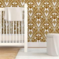 a white crib in front of a wall with gold and white designs on it