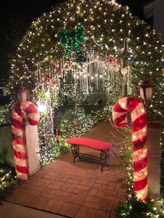 an archway decorated for christmas with lights and candy canes on the walkway leading up to it