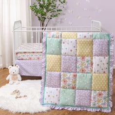 a baby crib with a teddy bear next to it and a quilt on the floor