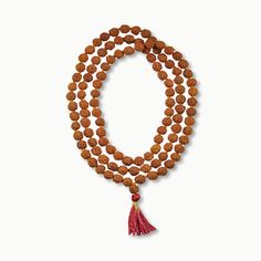 This simple hand-crafted mala featuring a deep red tassel, is made of 108 knotted Rudraksha seed beads and is perfect for your everyday ritual and mediation. Legend has it that the first Rudraksha seeds were created from tears of Lord Shiva as they fell on the earth and formed into a tree. Rudraksha seeds have wonderful spiritual and medicinal properties and, you can feel their power as you count through the beads one by one to recite your chosen mantra or intention. The number 108 holds spiritu Traditional Mala With Gemstone Beads For Healing, Spiritual Gemstone Beads Mala For Puja, Spiritual Gemstone Mala For Puja, Red Mala For Meditation With Round Beads, Hand-strung Spiritual Mala For Puja, Holistic Wooden Beads Mala For Festivals, Red Round Beads Mala For Meditation, Red Mala With Round Beads For Meditation, Spiritual Mala With 8mm Beads For Rituals