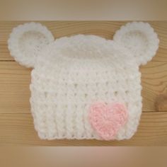 a crocheted bear hat with a pink heart on the front and ears attached to it