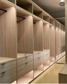 an empty walk in closet with wooden shelves and drawers on the wall, along with lights