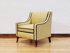 a yellow chair sitting on top of a hard wood floor next to a white wall