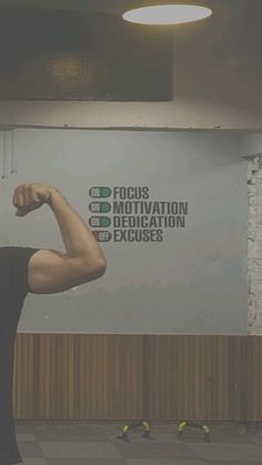 a man is flexing his muscles in front of a sign that reads focus motivation dedication exercises