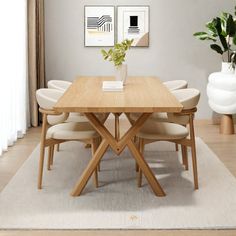 a dining room table with white chairs and a plant in a vase on the side