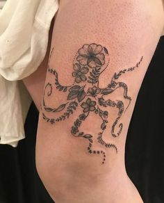 an octopus tattoo with flowers on it's arm and legs is seen in this image