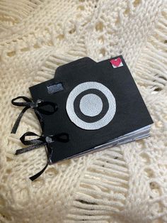 a black book with a white circle on it sitting on top of a knitted blanket