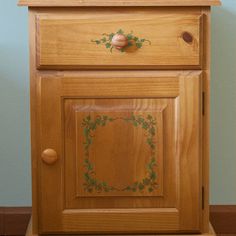 a wooden cabinet with an ornate design painted on the door and drawer knobs is shown