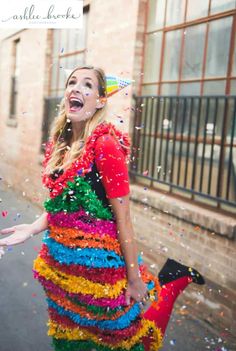 a woman in a multicolored dress is walking down the street with confetti on her face