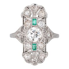 Finely detailed vintage Art Deco emerald & diamond ring (circa 1920s to 1930s) crafted in platinum.   Centre set old European cut diamond is estimated at .90 carats, accented with 12 estimated 0.05 carat old mine cut diamonds. The total diamond weight is estimated at 1.50 carats (estimated at I-J colour and VS2-SI2 clarity). Two emeralds total an estimated 0.10 carats. The emeralds are in good condition with a few nicks evident and general wear visible under a 10x loupe.    The elongated mount w Art Deco Emerald Diamond Ring With Accents, Art Deco Emerald Ring With Center Stone, Vintage Green Diamond Platinum Ring, Vintage Green Diamond Ring In Platinum, Vintage Emerald Ring With Diamond Accents, Heirloom Platinum Emerald Ring With 17 Jewels, Antique Emerald Diamond Ring With Brilliant Cut, Heirloom Emerald Ring With 17 Jewels In Platinum, Art Deco Emerald Ring With Platinum