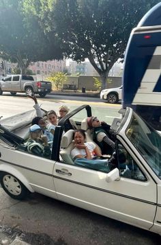 a group of people sitting in the back of a white car next to a bus