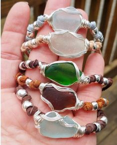 four different colored sea glass bracelets on someone's hand