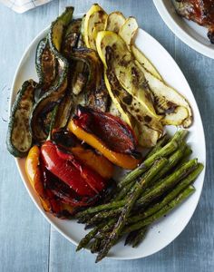 grilled vegetables on a white plate next to green beans and asparagus spears