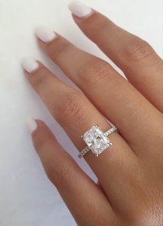 a woman's hand with an engagement ring on it and a diamond in the middle