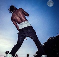 a man on a skateboard performing a trick in the air with other people watching