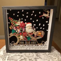 a santa clause sleigh with christmas decorations on it in a shadow box frame