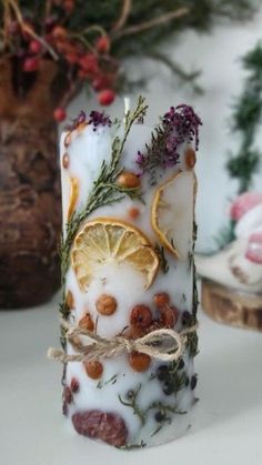 a candle that has been decorated with dried herbs and lemon slices