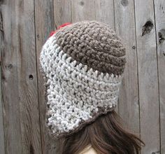 a woman wearing a crocheted beanie hat on top of a wooden fence