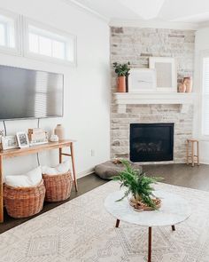 a living room with a fireplace, television and plants in baskets on the coffee table