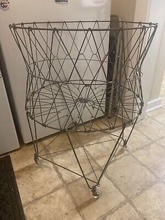 a wire basket sitting on the floor next to a refrigerator