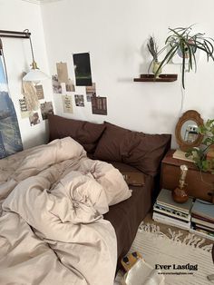 an unmade bed sitting in a bedroom next to a plant